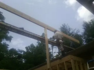 Carpenter setting a ridge beam over a new addition frame — Ice Dam Removal by Roofing Brothers in Promise City