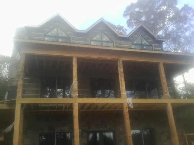 Dormers and porch framing on a large log home under construction — Roof Coating work by our crew in Promise City