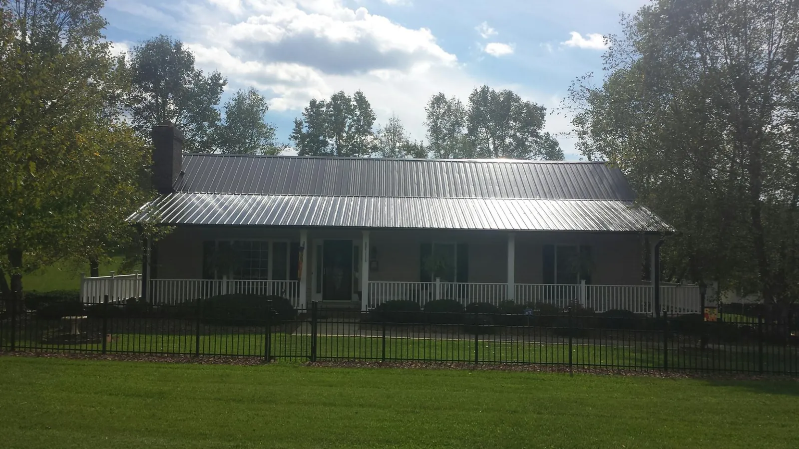 Gray metal roof on a brick ranch with a full width front porch — Gutter Guard Installation work by our crew in Promise City