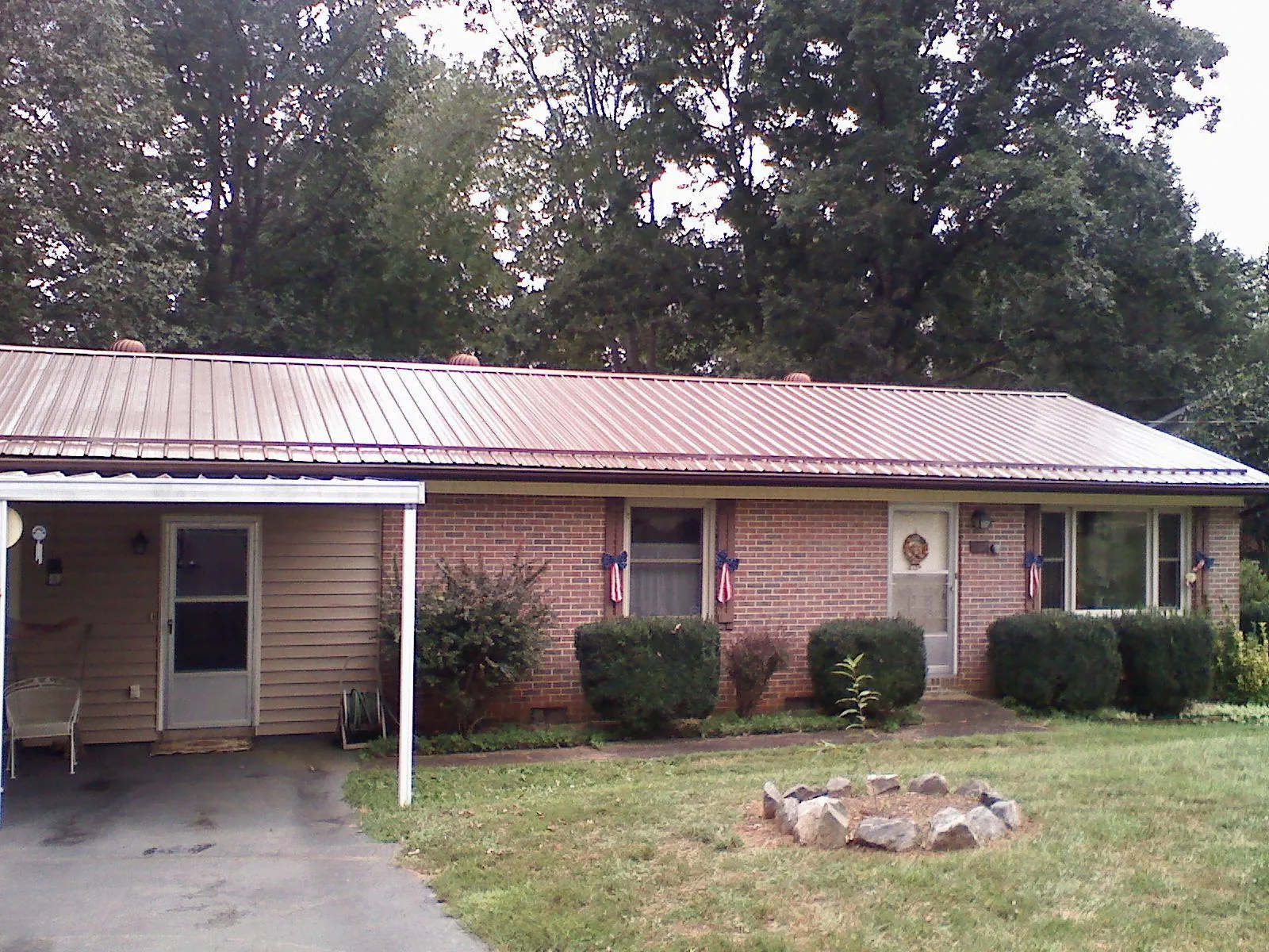 Bronze metal roof and carport on a brick ranch home — Roof Repair work by our crew in Promise City