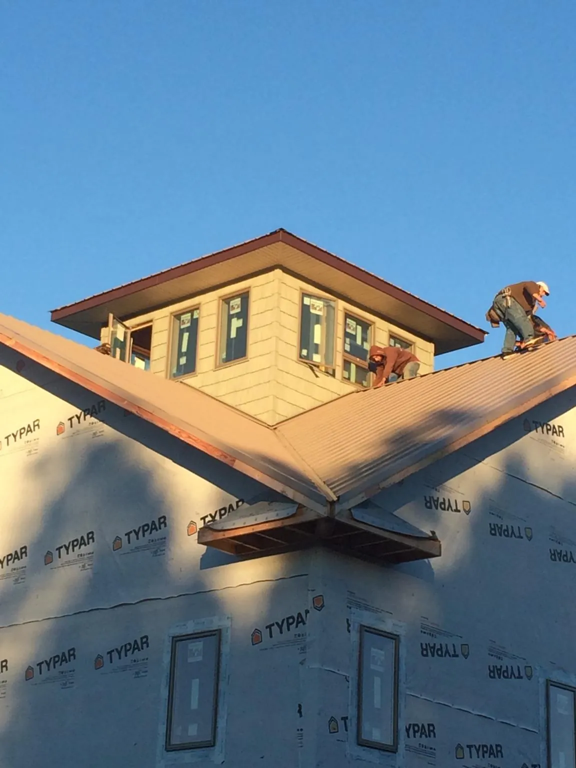 Roofers working around a rooftop cupola on a new metal roof at sunset — Roof Waterproofing in Promise City by Roofing Brothers